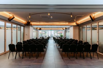 Modern conference room with rows of black chairs facing a bright window at Amora Herencia Riverwalk Melbourne