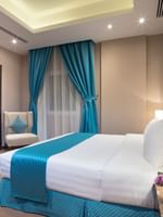 TV facing bed with side tables near window in Standard room at Naviti By Warwick Dammam