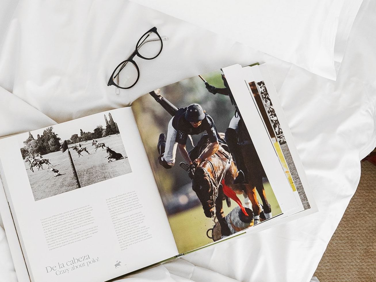 Book & a pair of spectacles on a bed at Hotel Emperador Buenos