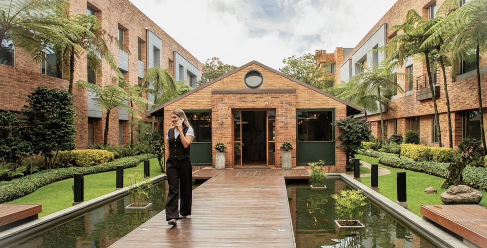 Employee walking on a boardwalk over a water feature at Habitel Prime Hotel