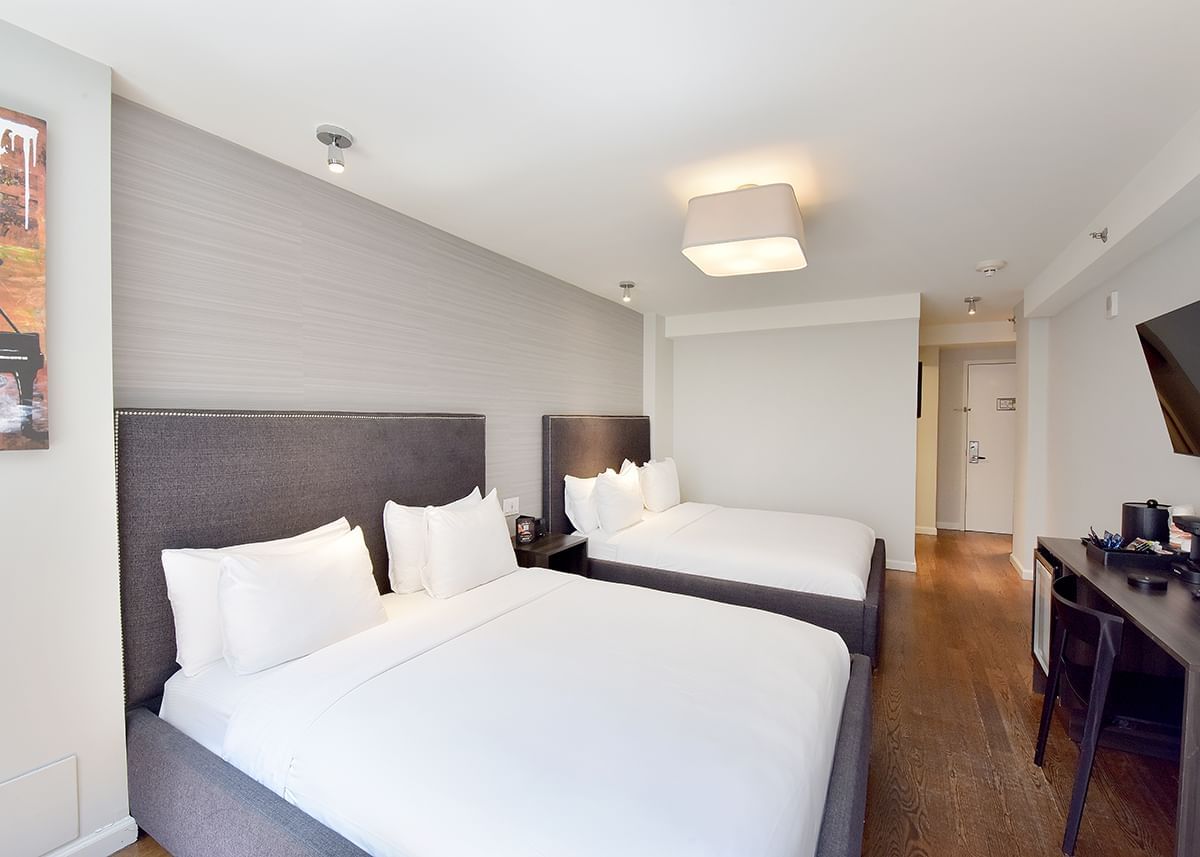 A hotel room with two twin beds, a desk, and a flat-screen TV.