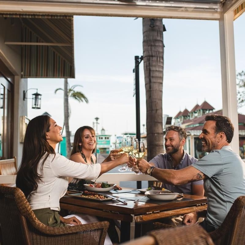 Group of friends toasting with wine glasses at an outdoor restaurant in Las Vegas to Catalina: Your Ultimate Island Getaway.