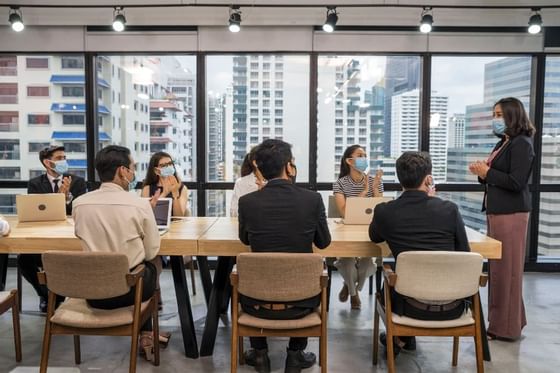 corporate people having a meeting in a boardroom with a view of a city scape in the windows
