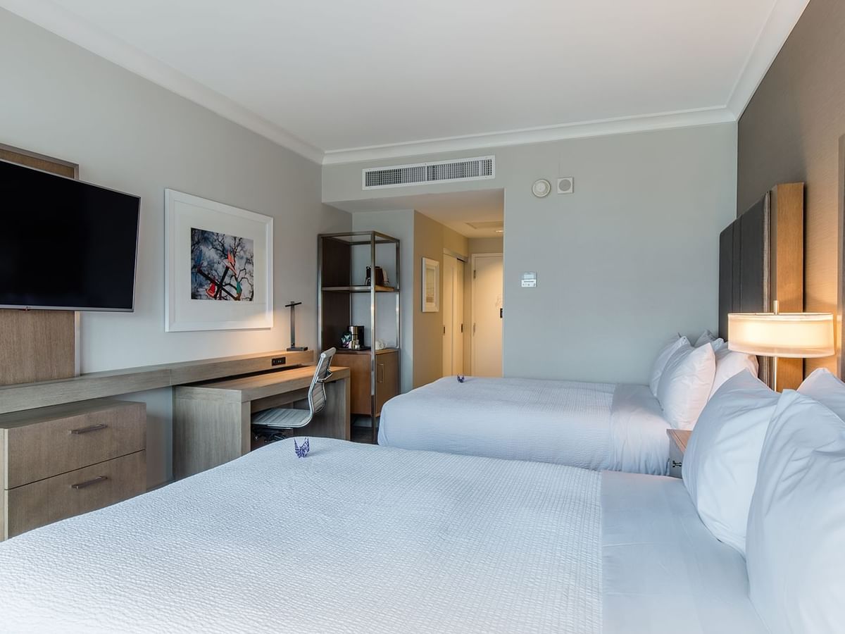 Hotel guestroom with two beds, TV, and desk