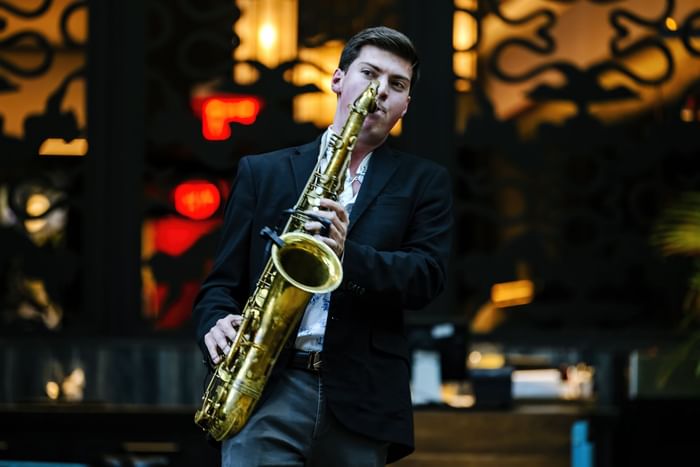 Man in full suit playing a saxophone against a backdrop of colorful lights at The Diplomat Resort