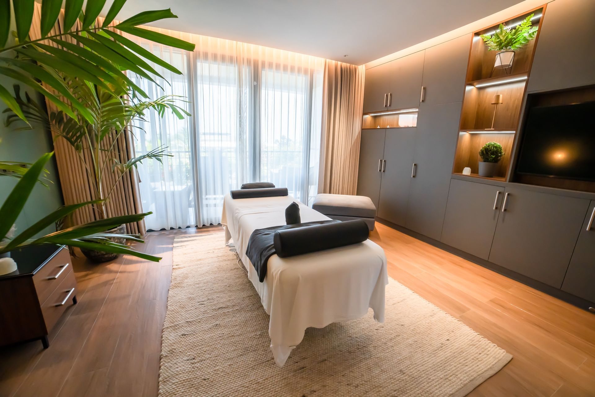 Massage room with a treatment table, soft lighting, greenery in The Rock Spa at Golden Rock Resort