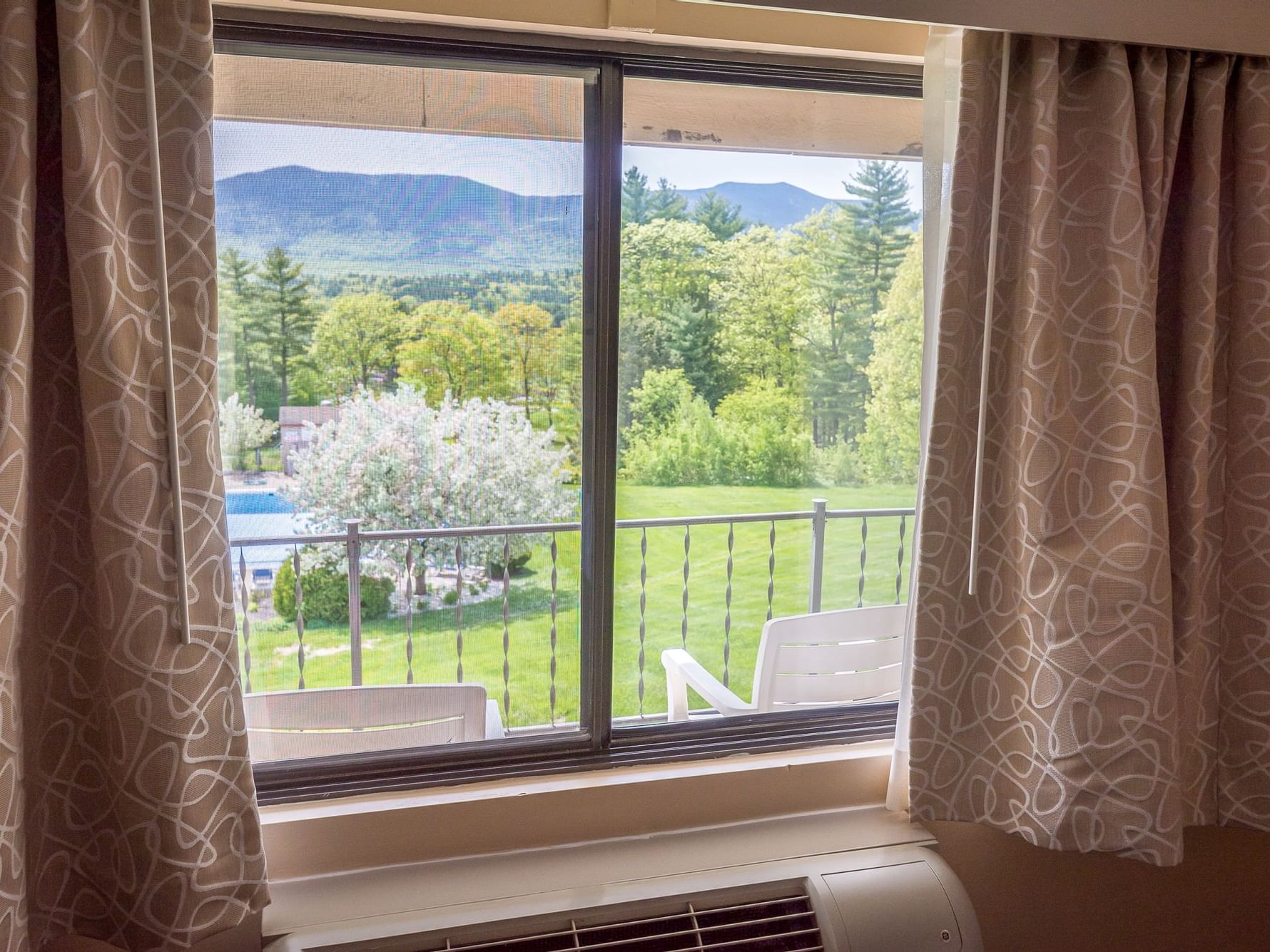 Window view of balcony and lush greenery with mountains at Fox Ridge Resort in Conway.