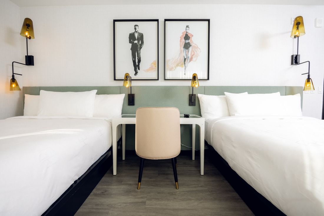 A hotel room with two twin beds, a desk, and chair.