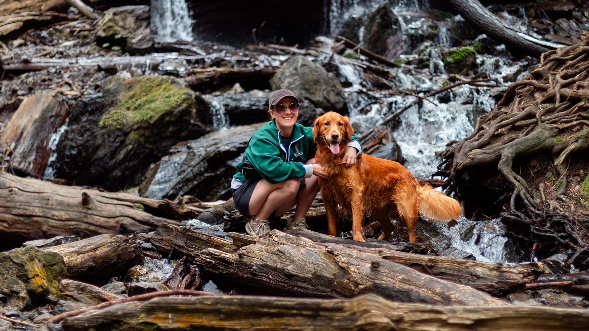Woman and golden retriever dog near a waterfall.