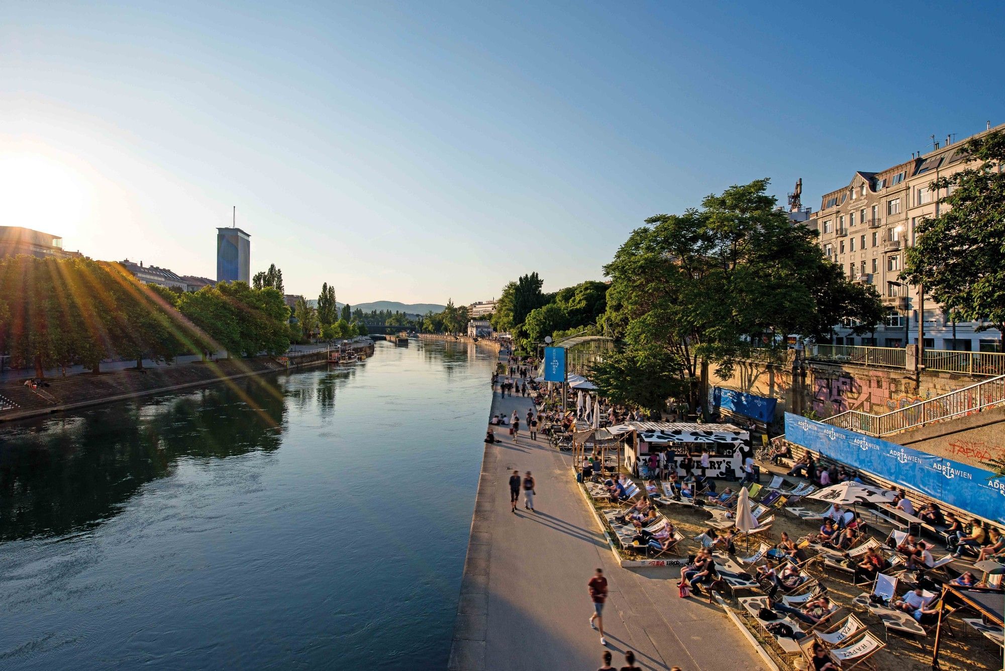 Vienna Danube Canal with bars, promenade and relaxed summer evening at sunset