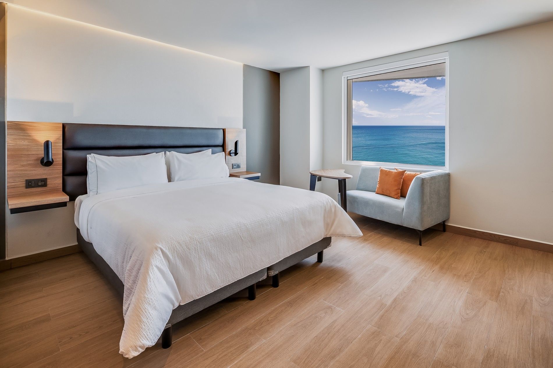 Habitación luminosa con cama king y área de estar con vista a la ciudad en Fiesta Inn