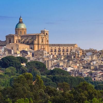 Panoramablick auf die historische Stadt Modica in Sizilien mit einer Kuppelkirche und vielen Gebäuden.