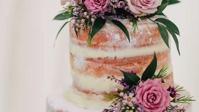 Multi-layered naked cake, adorned with fresh pink and purple roses at The Sebel Mandurah
