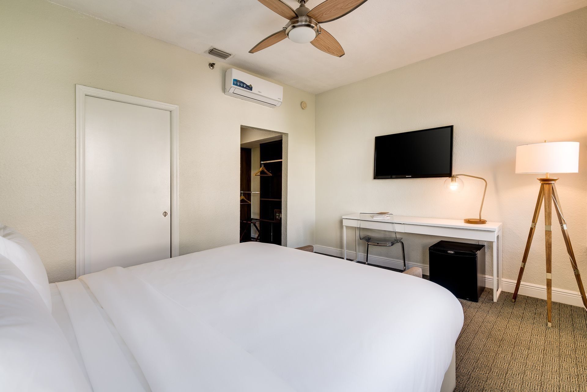A hotel room with a bed, TV, desk, and closet.