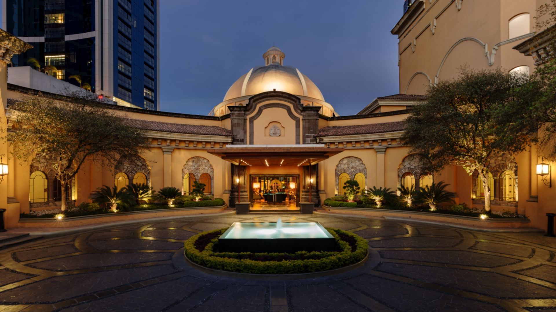 Stunning illuminated dome and entrance featuring a fountain during the evening at Quinta Real Monterrey