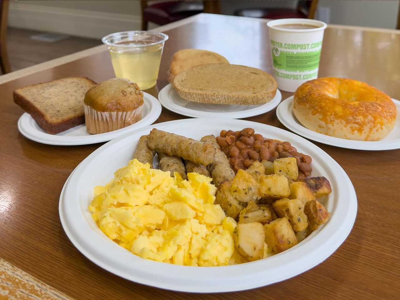 Breakfast spread with scrambled eggs, sausages, potatoes, beans, toast, muffin, and beverages at Coast Edson Hotel.