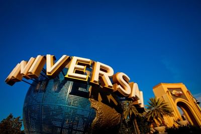 Large Universal globe by palm trees under a clear blue sky at Universal Studios Florida near Galleria Palms Hotel