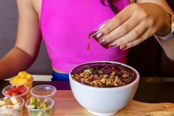 A woman drizzling honey on top of a delicious acai bowl at Rosen Inn International in Orlando.