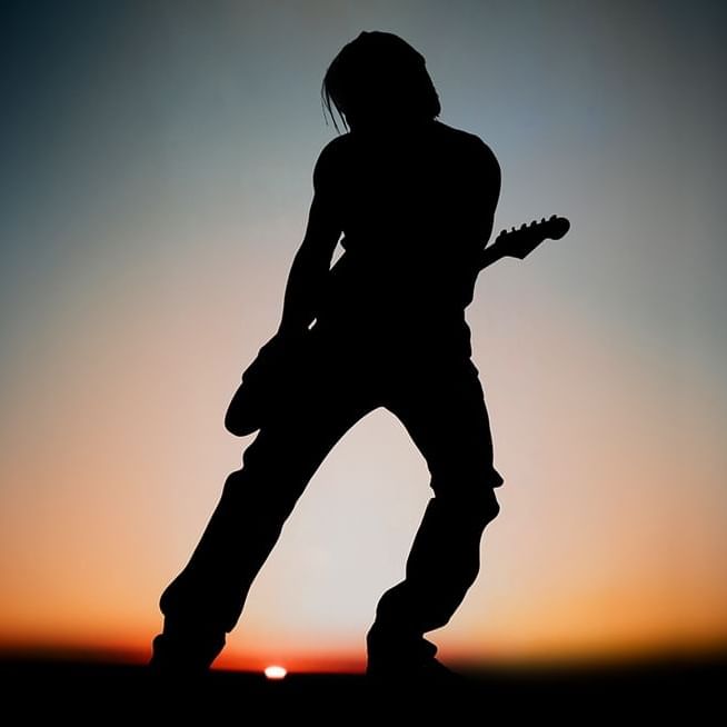 Keith Urban performing live on stage with guitar under bright stage lights
