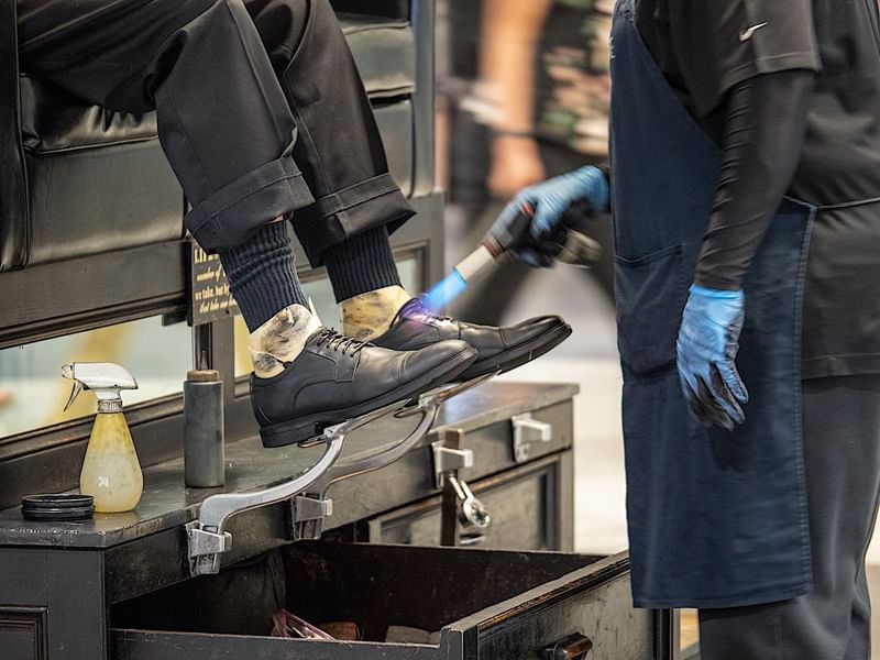 A guest receiving a professional shoe shine service at El Prado Hotel, ensuring polished footwear