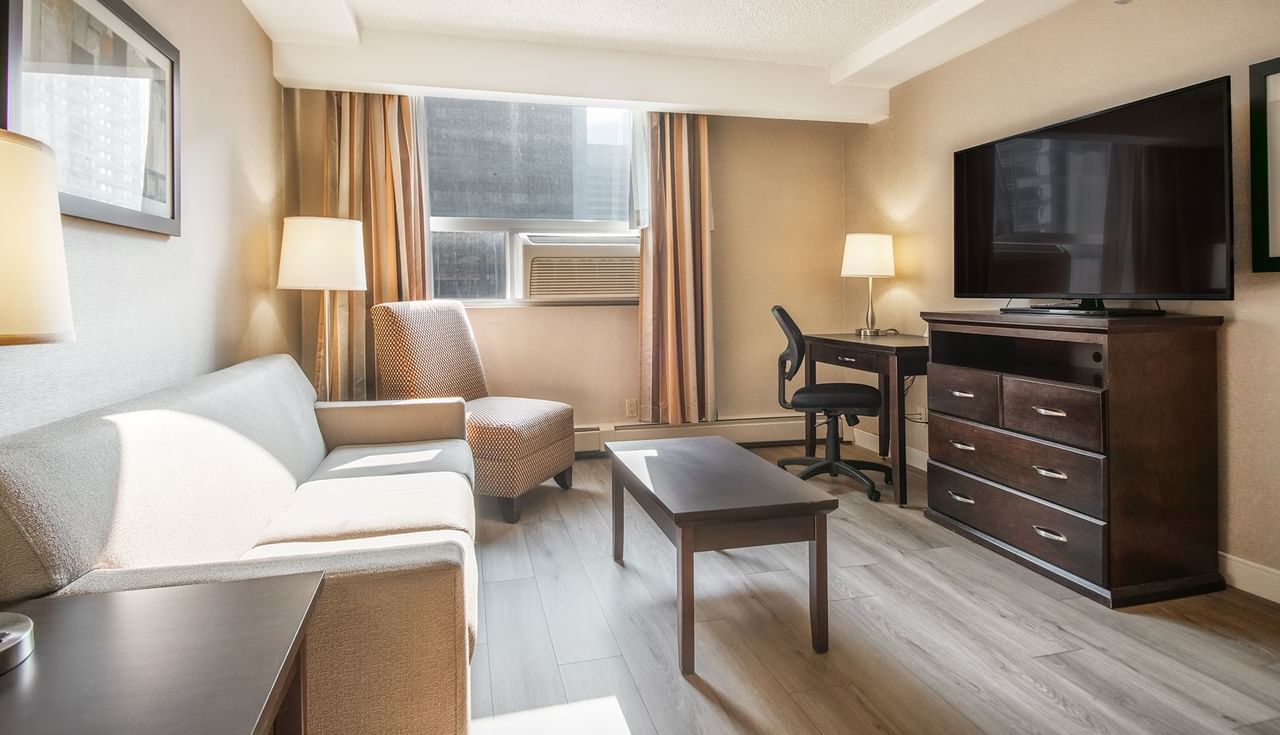Hotel suite living room with TV, couch, table, work desk and chair