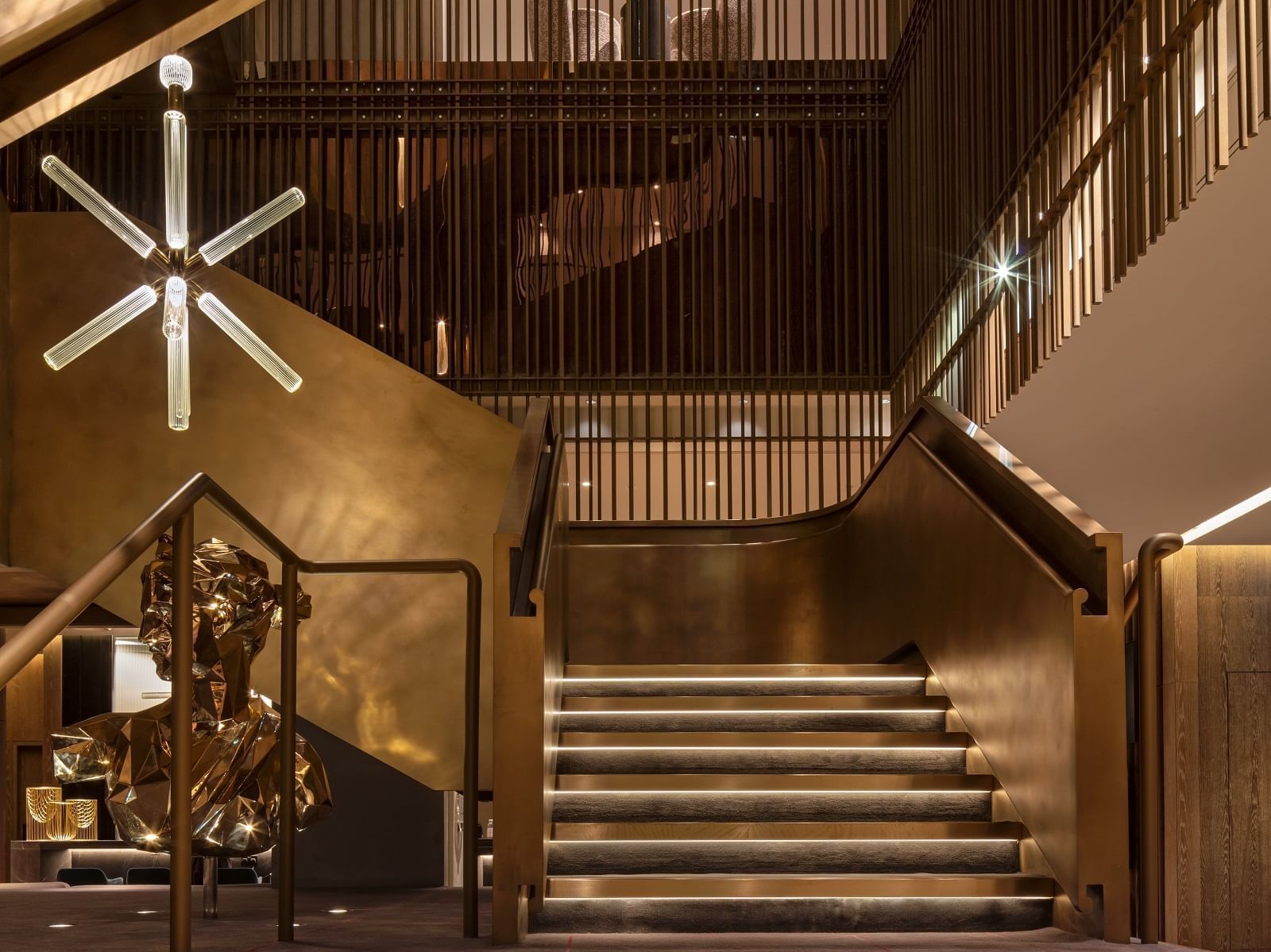 Luxurious grand staircase featuring golden accents and modern design in The Gallery at The Londoner Hotel