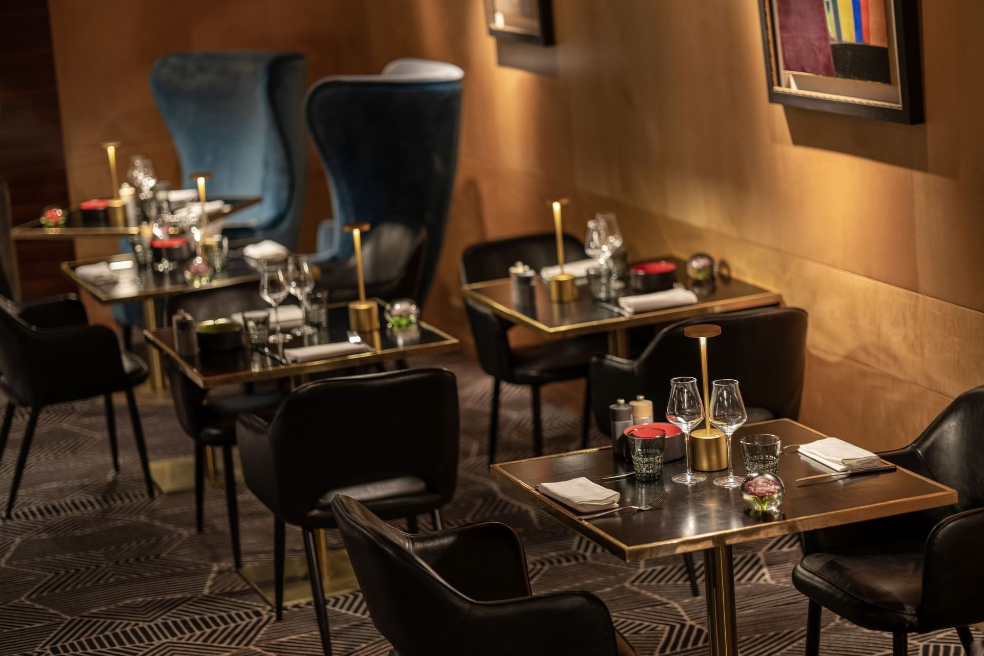Black chairs around set dining tables under warm lights at Restaurant, Bar & Terrace Le W, an elite Restaurant in Paris