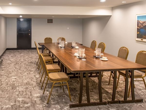 A long table with chairs and drinks in a meeting room.