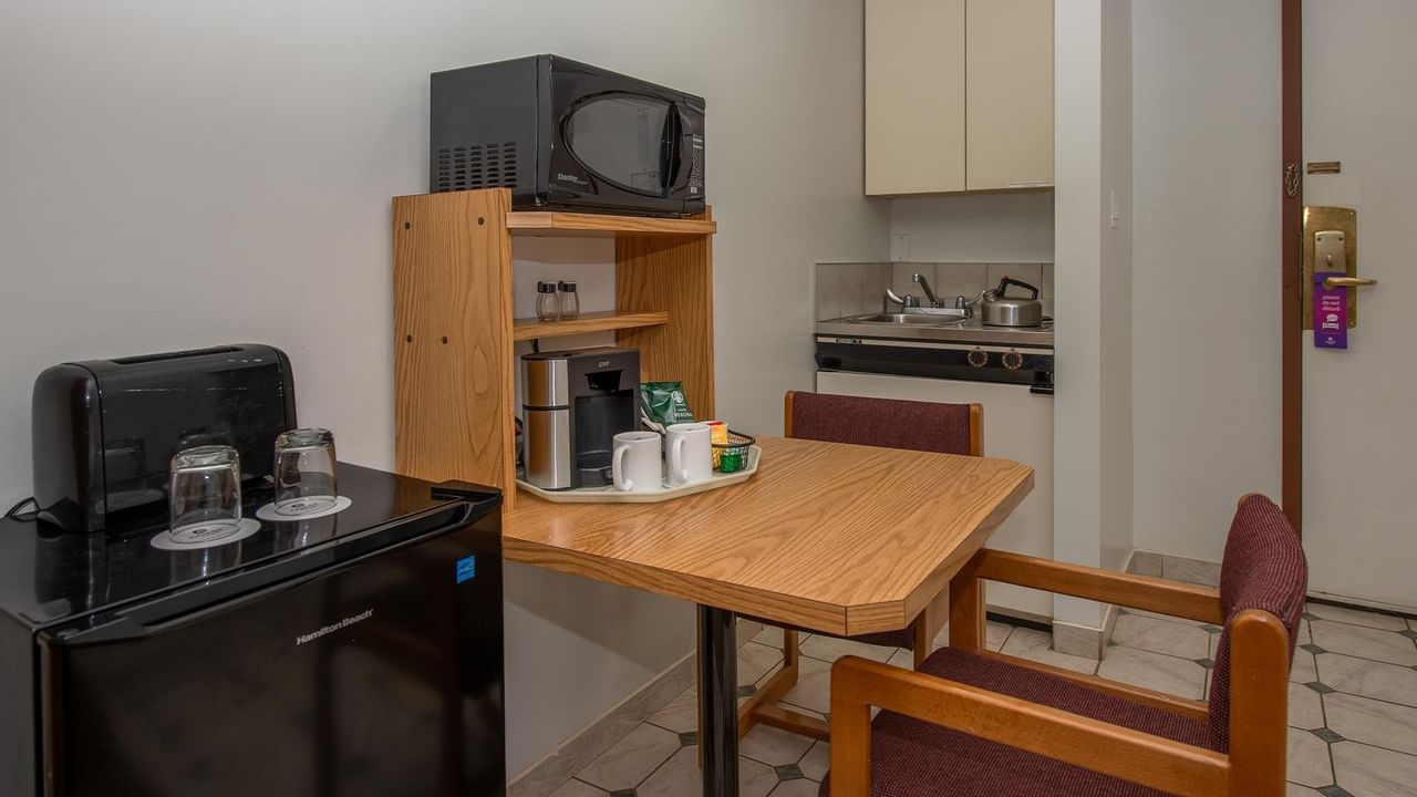 guest room kitchenette with coffee maker, microwave, mini fridge and dining table at Coast Whitecourt Hotel