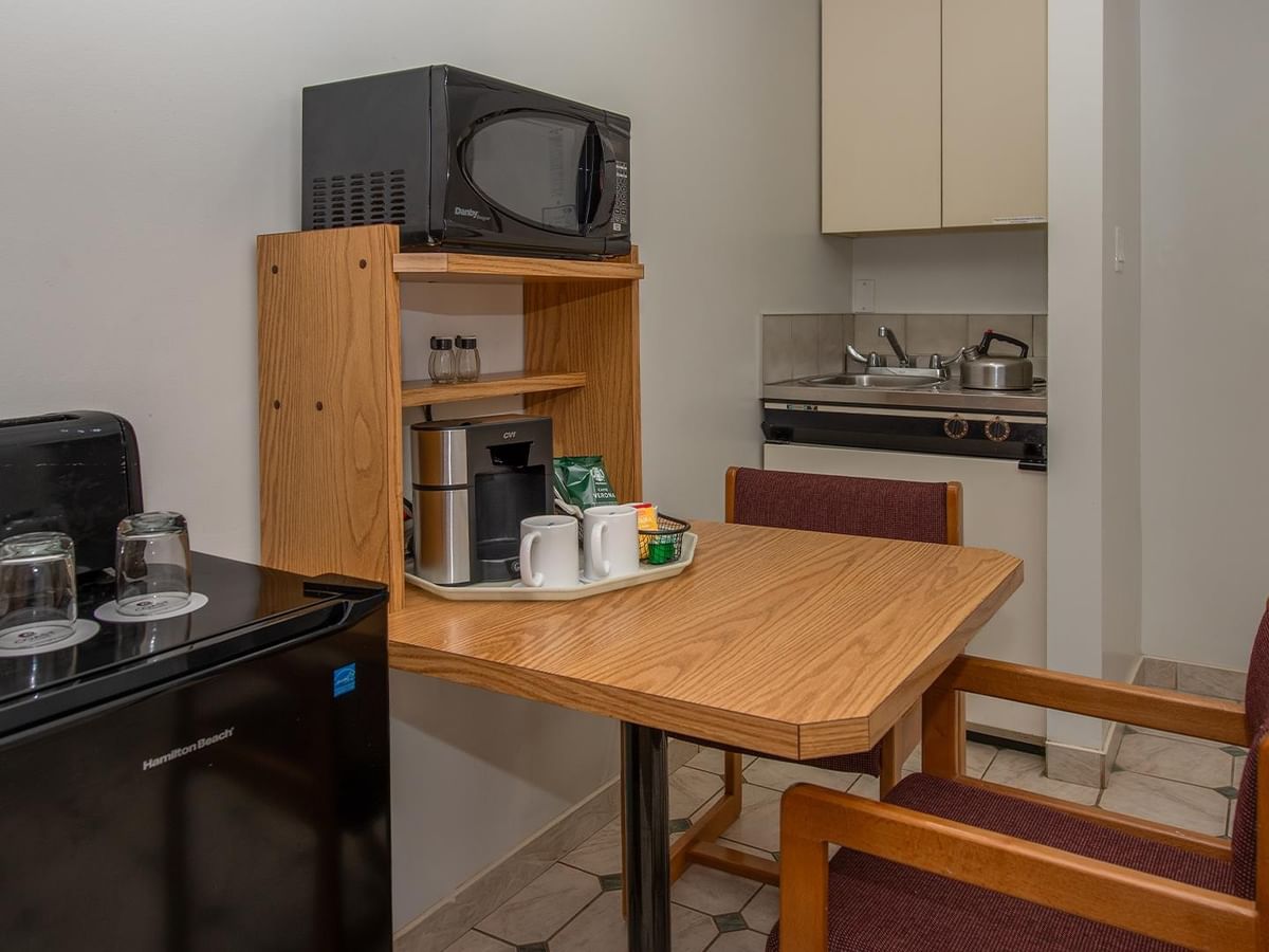 In-room kitchenette and dining area with a microwave, coffee maker, sink and table