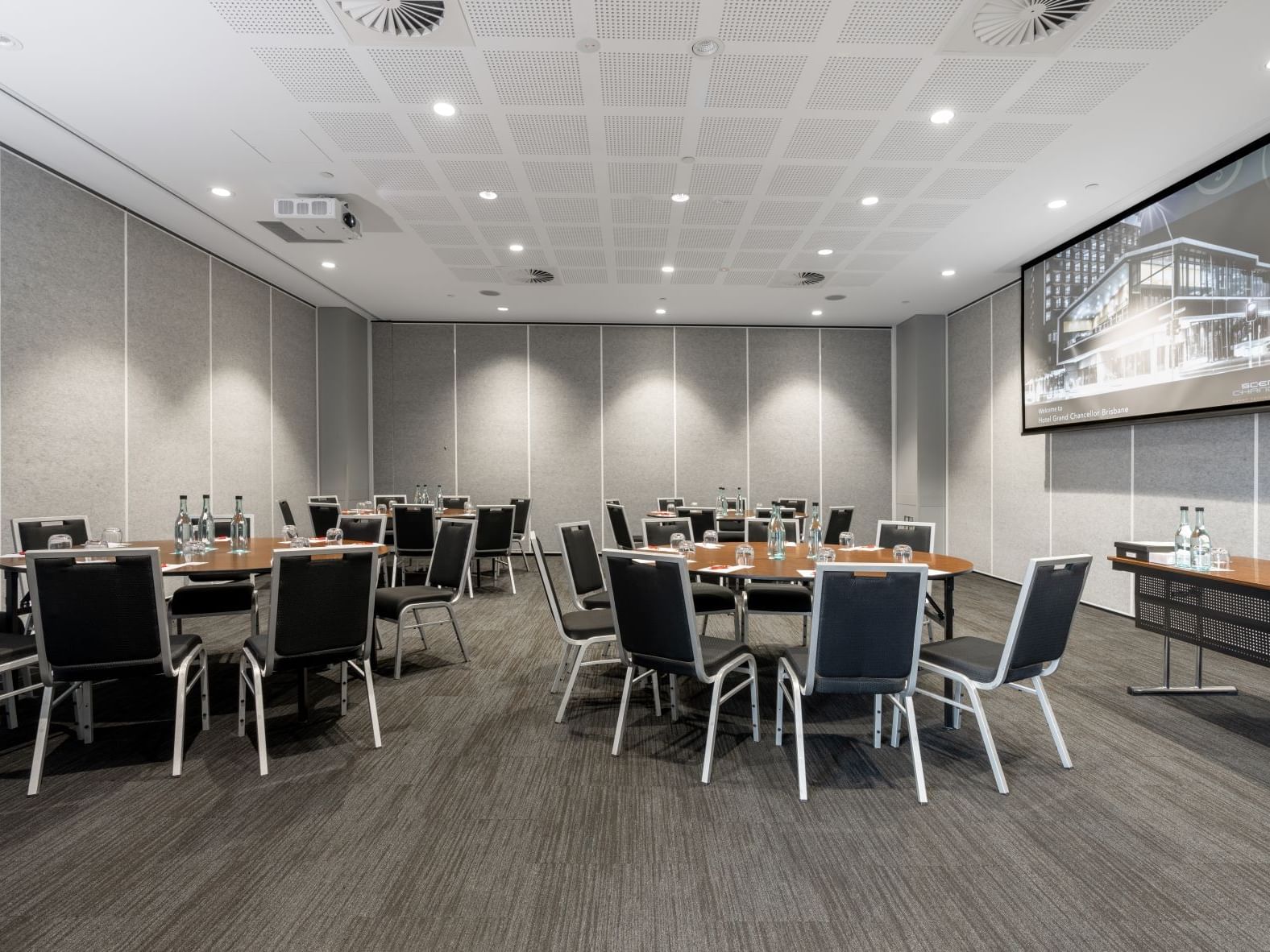 Modern Brisbane meeting room with round table setup, presentation screen, and flexible conference facilities at Hotel Grand Chancellor Brisbane.