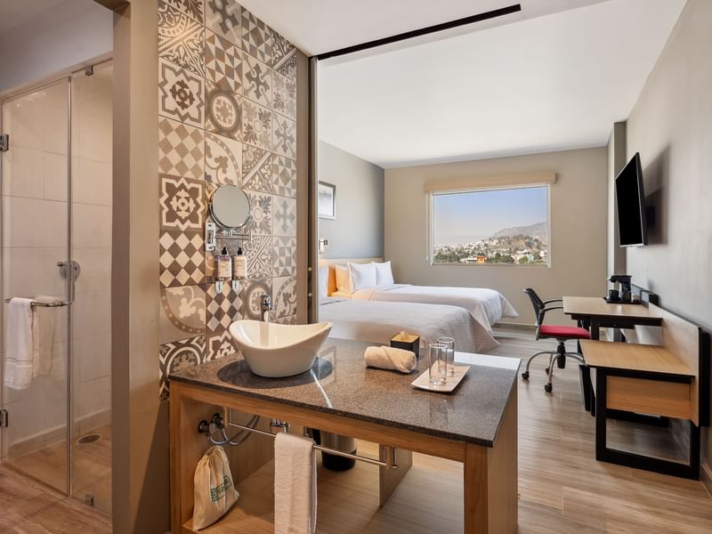 Two beds with a sink area and a glass door to the bathroom in the Standard Double Room at Gamma Hotels