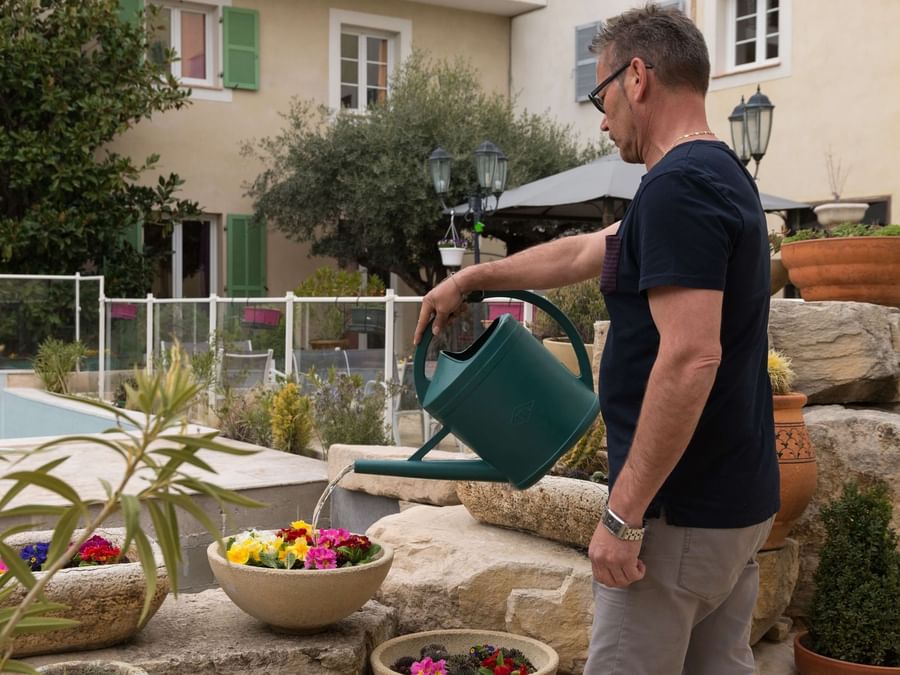 A gardener watering the flowers at Hotel Le Village Provencal