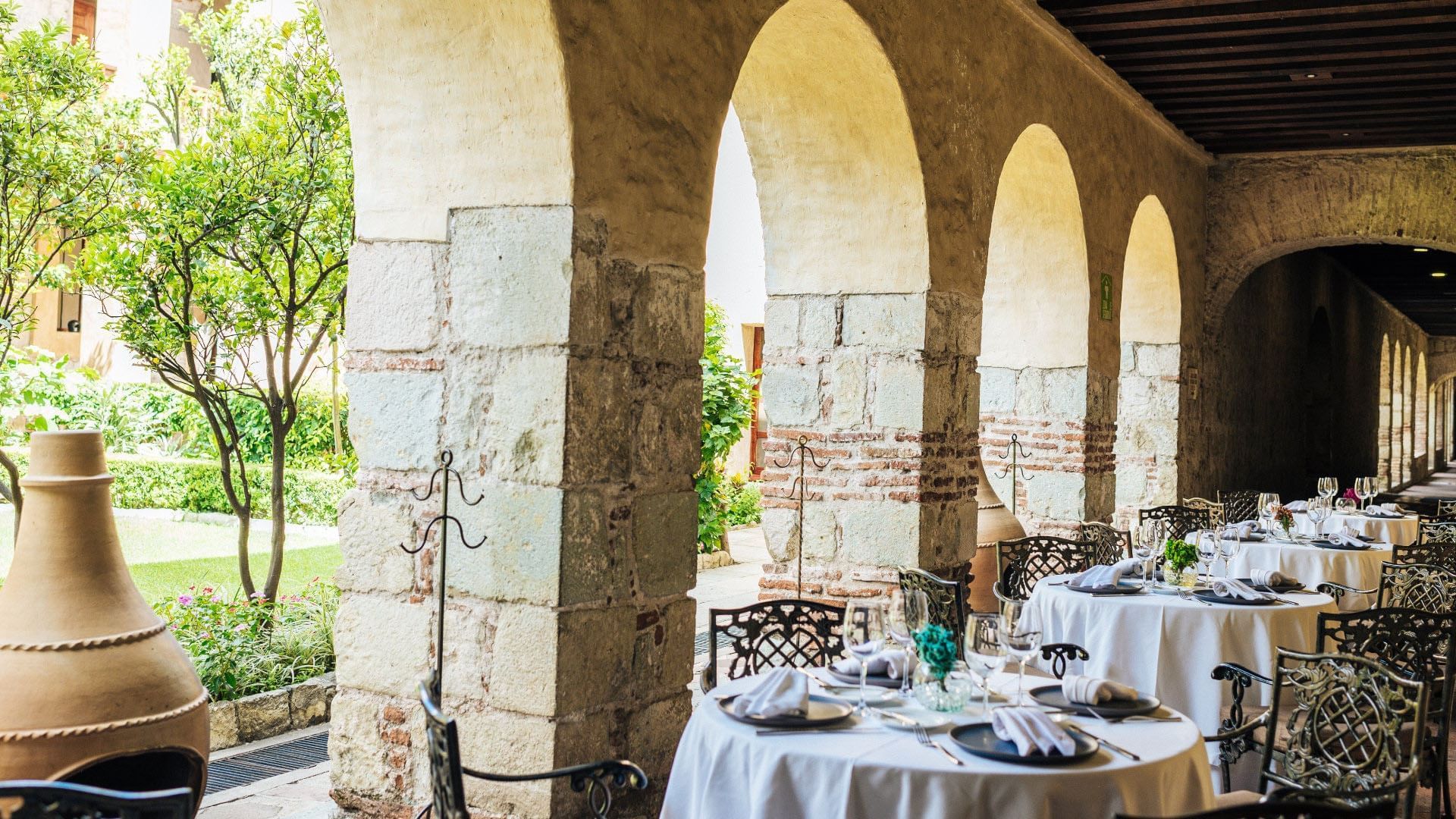 Scenic outdoor patio dining area in El Refectorio with stone arches and garden views at Quinta Real Oaxaca