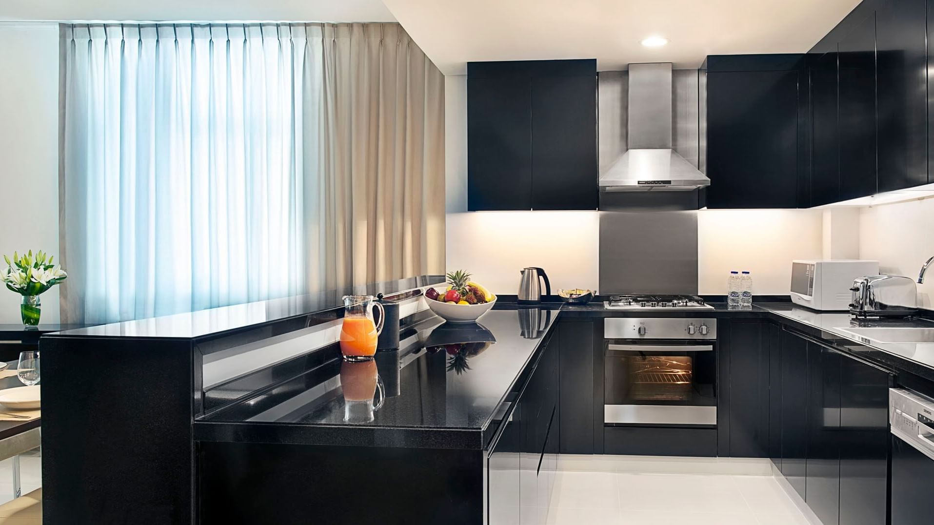 Kitchen with black interior & appliances in Two Bedroom Suite at DAMAC Maison Cour Jardin