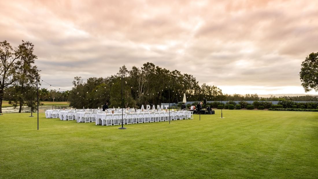 Outdoor event setup on a grassy field with white chairs, tables