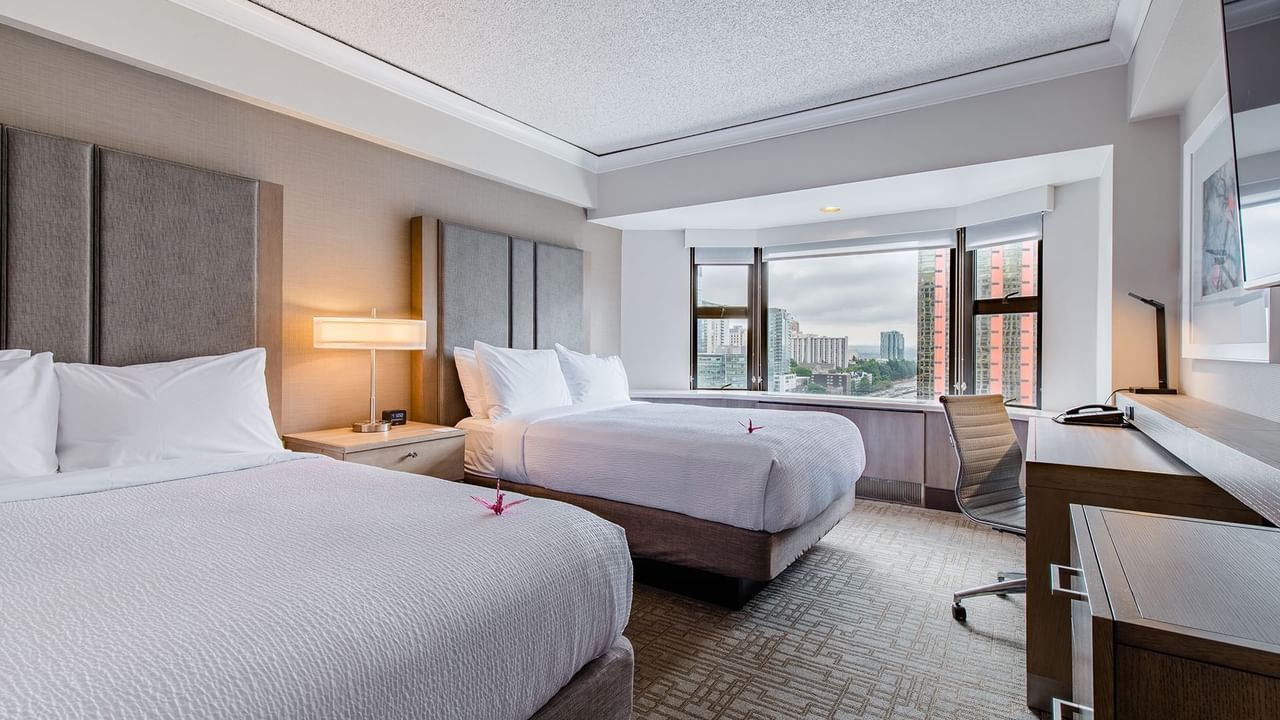 Hotel guestroom with two beds, TV, and desk