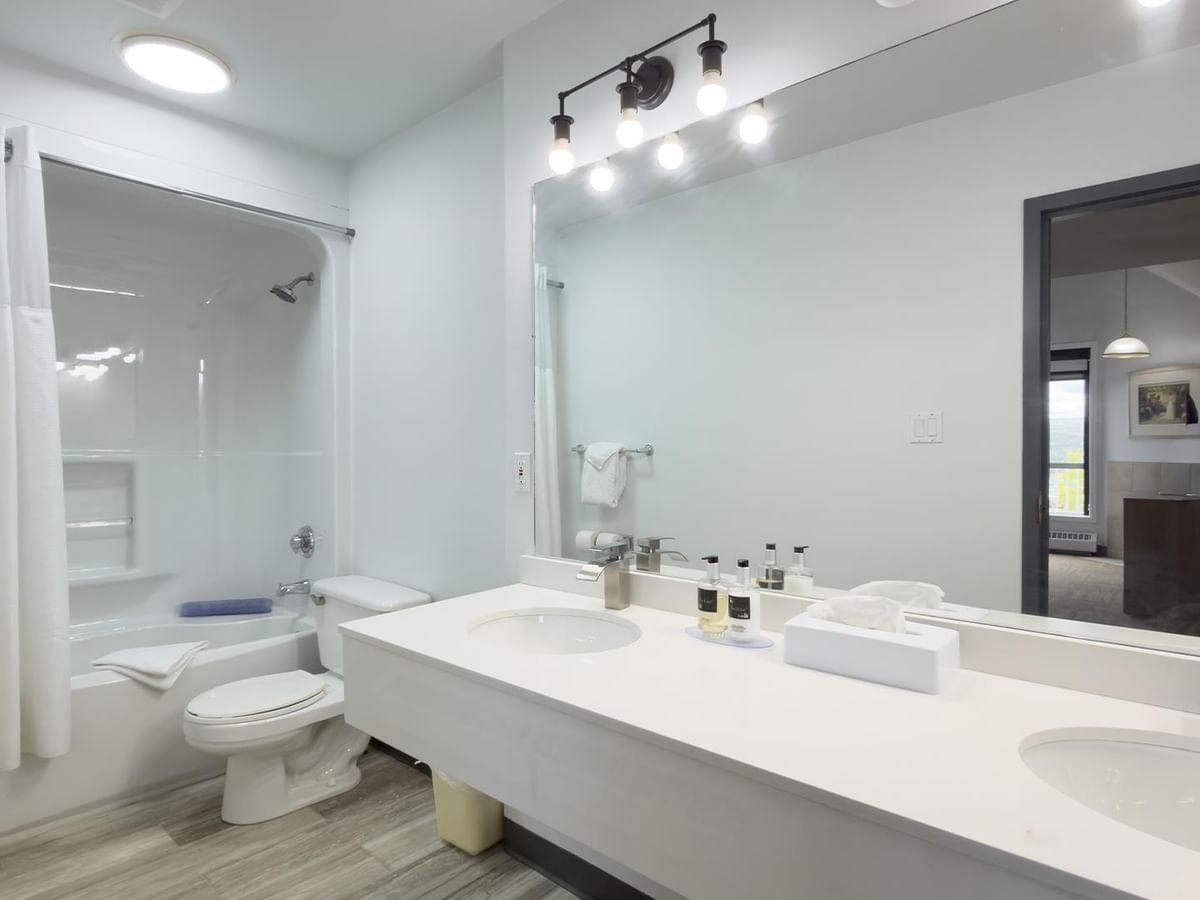 Coast Suite bathroom with double vanity, large mirror and tub-shower combo.
