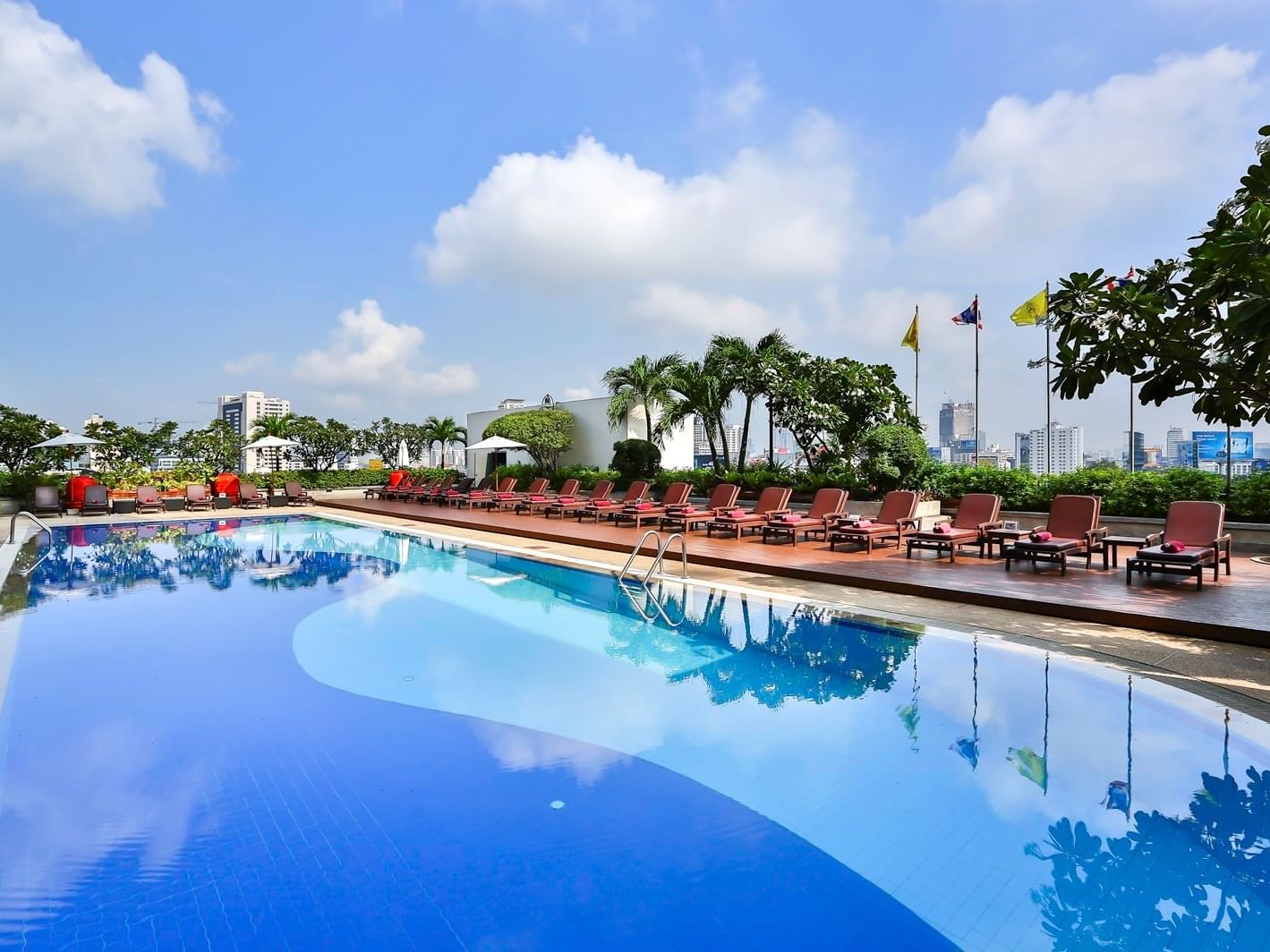 Outdoor swimming pool with lined lounge beds at Eastin Hotels
