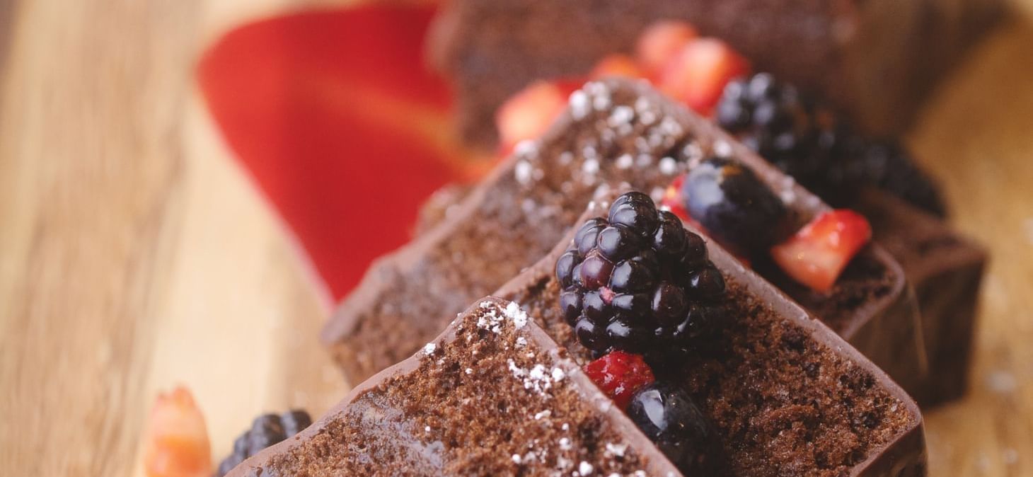 Sliced up chocolate cake dessert with diced strawberries, blueberries and black berries