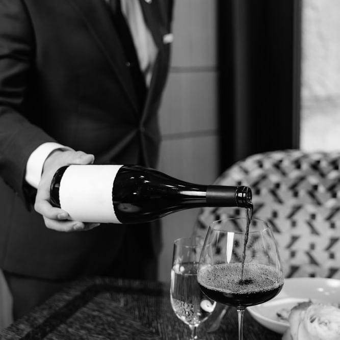 Wine Director pouring wine into a glass on a table at Umstead Uncorked Wine Tasting.