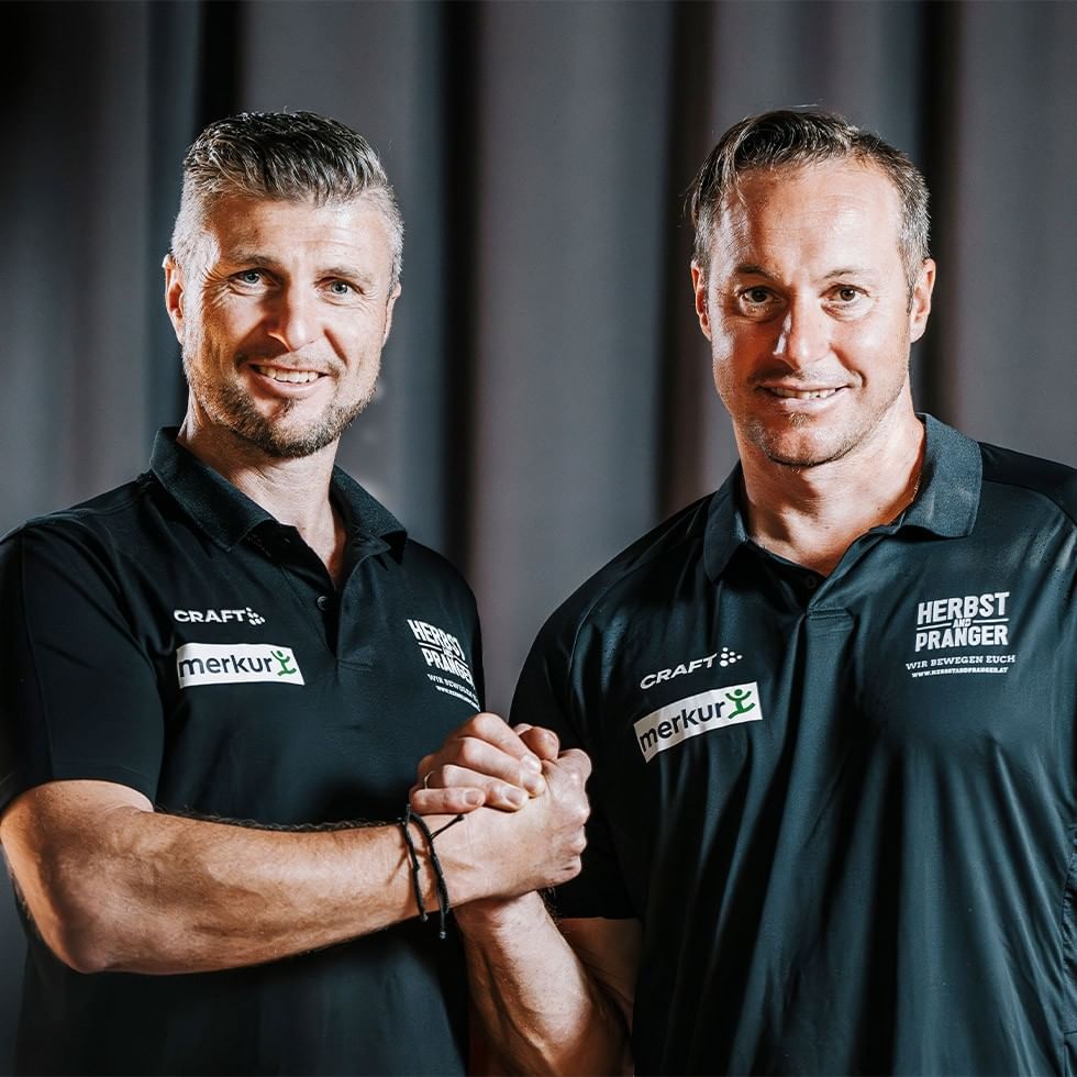 Two men in Merkur polo shirts smiling for the Herbst & Pranger Special offer.