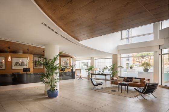 Lobby area with a reception desk, seating, plants, and large windows allowing natural light.
