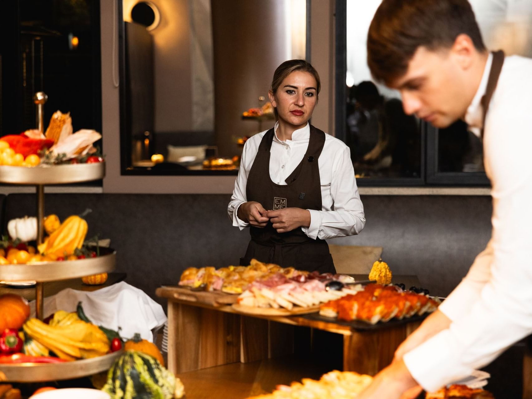 Two waiters standing in front of a buffet table filled with delicious food at EMME Restaurant