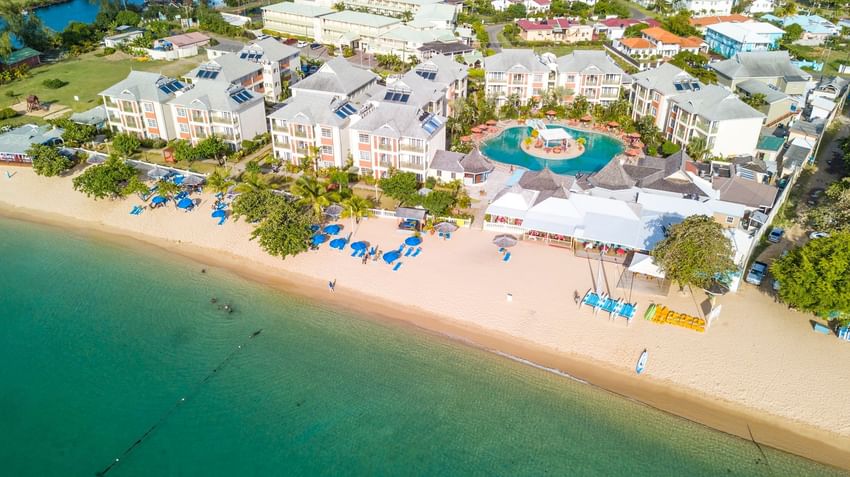 Aerial view of Bay Gardens Hotels and Resorts showing pool, sandy beach, blue umbrellas, clear waters, lush greenery