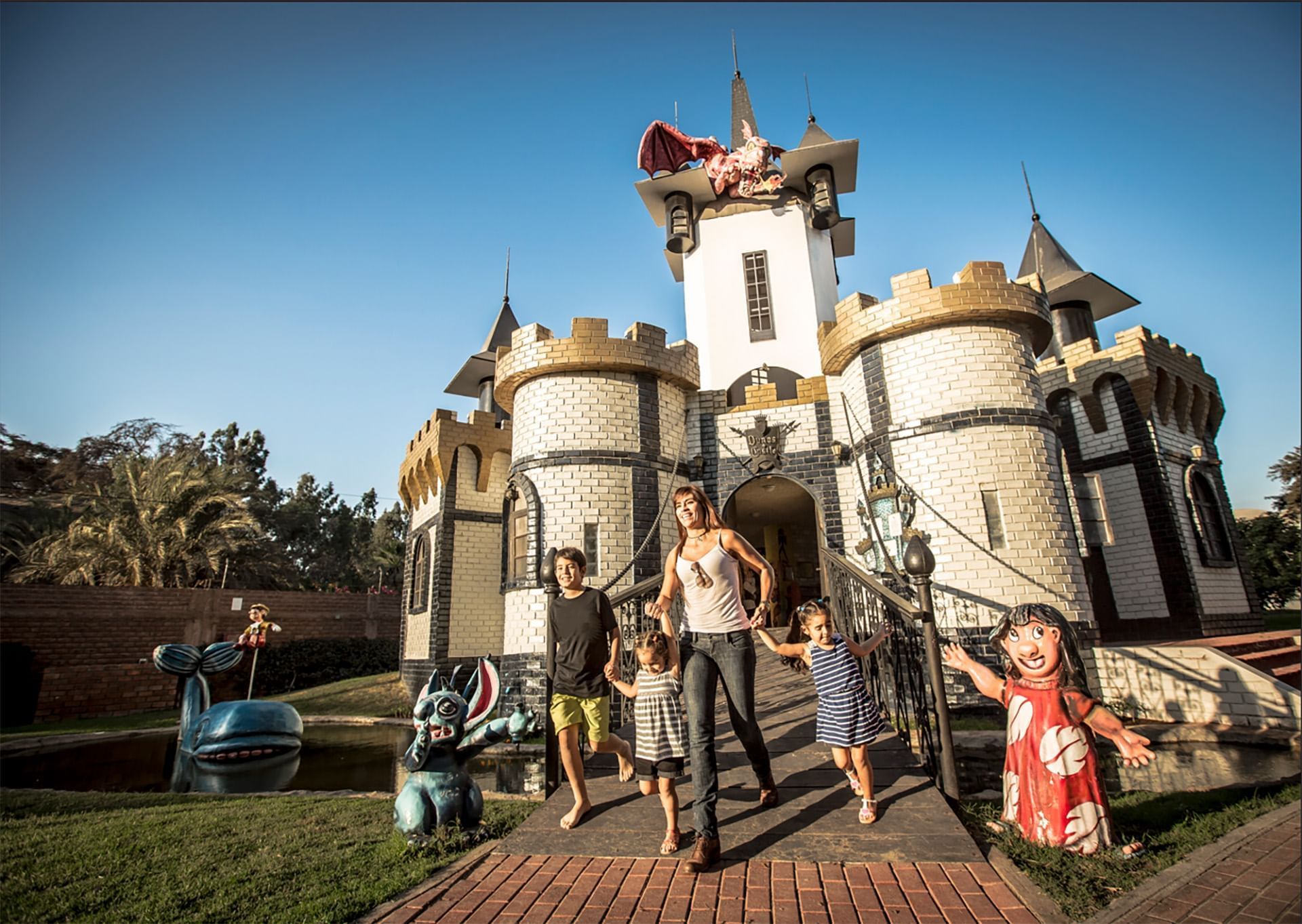 Family walks away from a whimsical castle with a dragon sculpture on top near Las Dunas Resort Ica