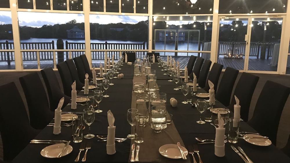 Dining table set-up with black glassware by a tranquil waterfront in Lily’s on the Lagoon at Novotel Sunshine Coast Resort