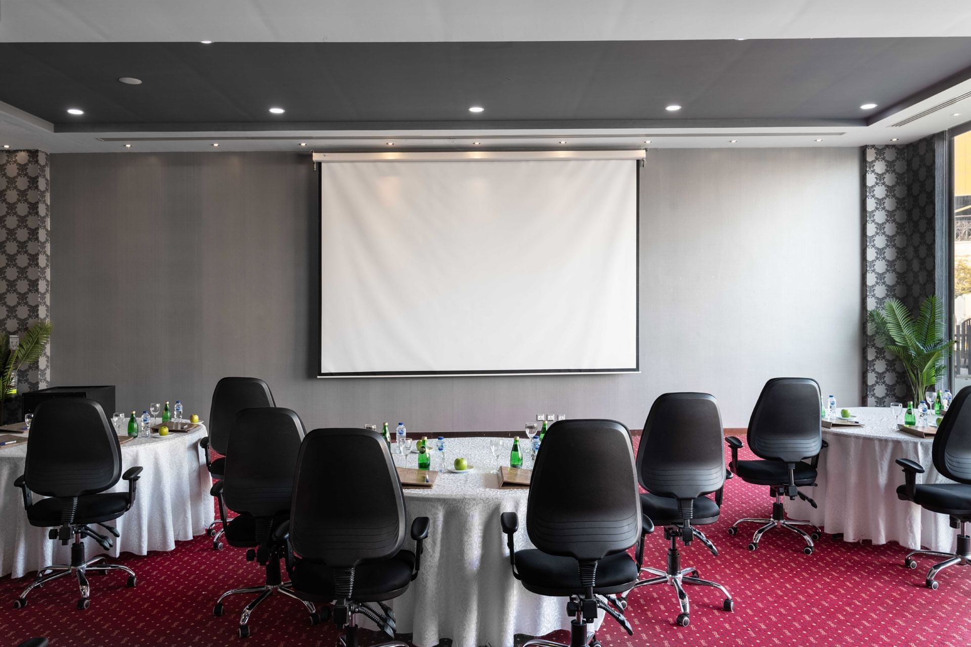Amarige 2 conference room featuring round tables, chairs, and a large projection screen at Warwick Hotels and Resorts