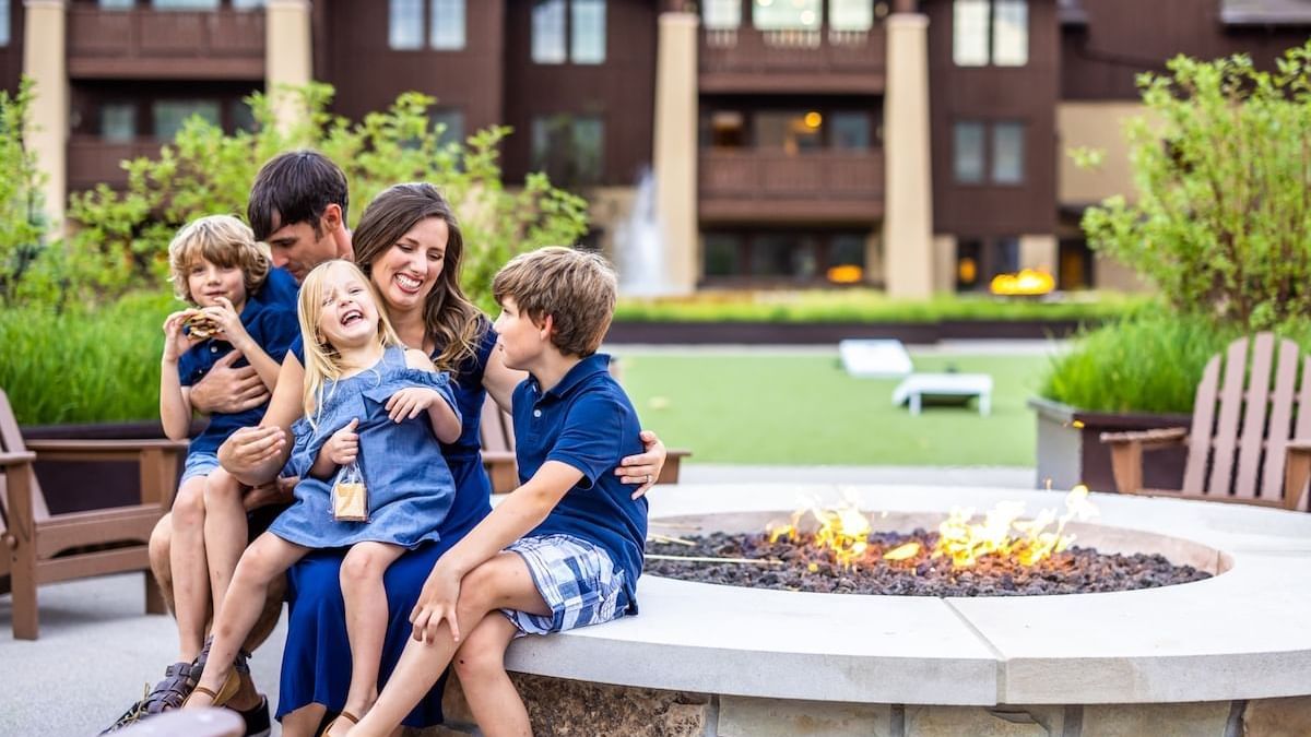 A family enjoying nearby the fireplace in the courtyard at The Chateaux Deer Valley