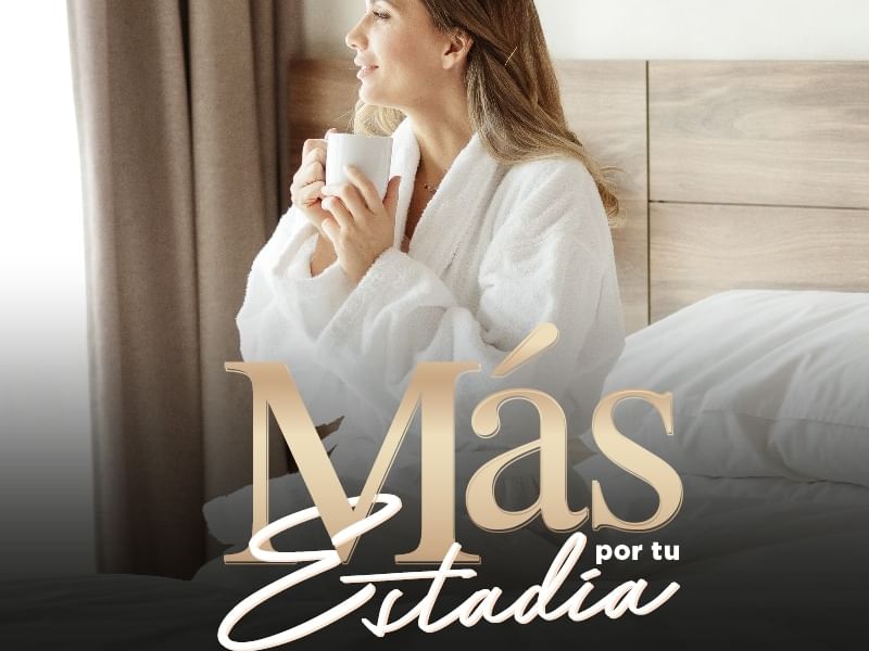 Woman in bathrobe holding a cup in a hotel room